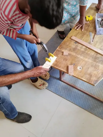 A close-up of a woodworking lesson, where a participant learns to use a clamp. Mastering basic tools is the first step towards becoming a confident fixer.