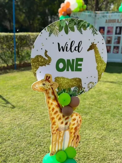 A "Wild One" decorative sign with a giraffe cutout, perfect for photo ops at a jungle-themed first birthday.