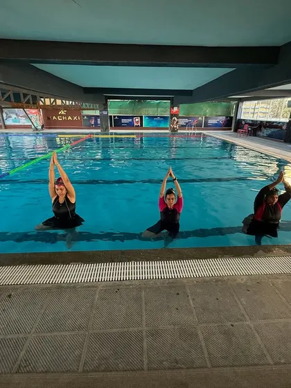 A group of women practicing a synchronized seated pose during an aqua yoga class. There's a beautiful sense of community and shared experience in these sessions.