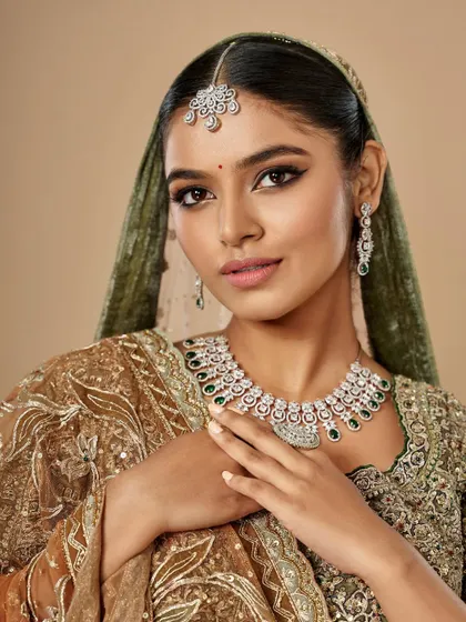 A close-up of the bridal glam created by Simran. The sharp winged liner and soft pink lip perfectly complement the green and gold tones of the outfit.