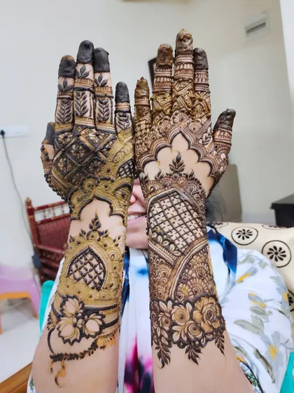 A happy client showing off her intricate design, which features architectural and floral motifs.
