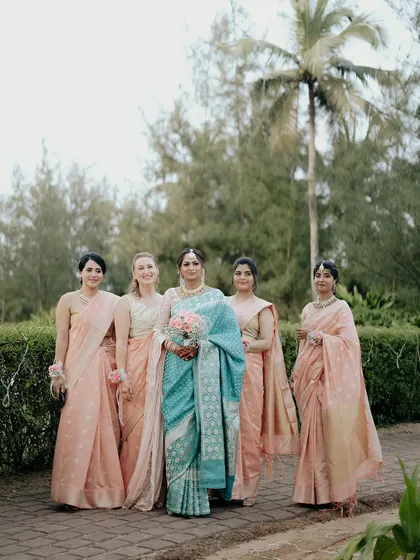 The bride, Ankita, with her bridesmaids in Goa. The color palette of her blue saree against their peach sarees is visually stunning.