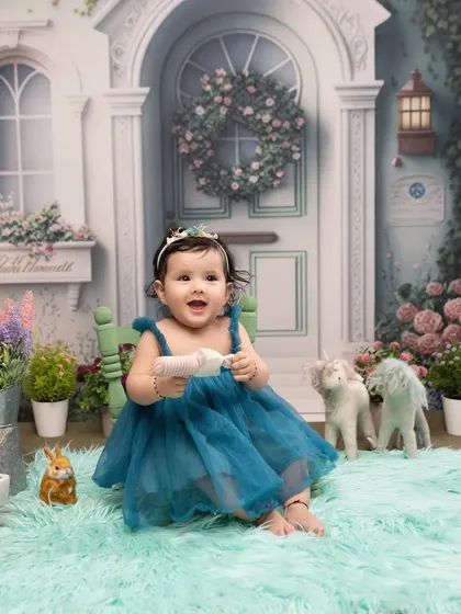 A storybook setting for a little princess. Her joyful expression is perfectly framed by our enchanting fairytale house backdrop, filled with flowers and whimsical details.