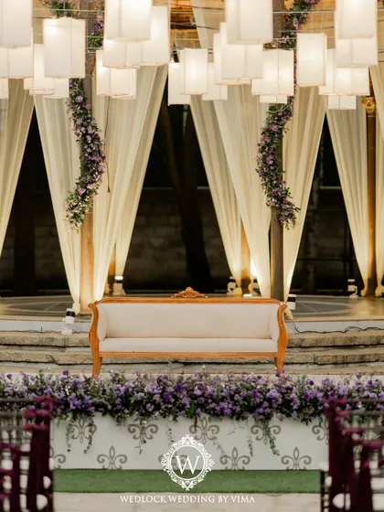 A simple yet elegant reception setup with soft lantern lighting and delicate drapes on the gazebo. The lush purple-themed florals and romantic centerpieces tied the whole look together.