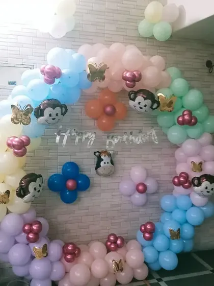 A playful monkey-themed ring decoration for a home party. The pastel balloons are decorated with cute monkey foil balloons and butterfly stickers.