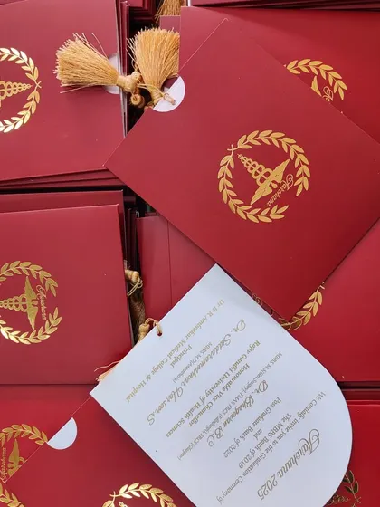 A formal and elegant invitation for a graduation ceremony, featuring a rich red cover with a gold foil emblem and a tassel.