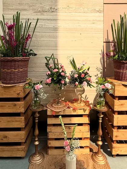 We love using different levels and textures. For this 80th birthday, we used rustic wooden crates to display wicker baskets and vases filled with pink gladiolus and roses.