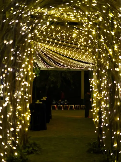 Imagine entering the party through this starry tunnel. We used arches wrapped in fairy lights to create a magical and immersive entrance for the cocktail night.
