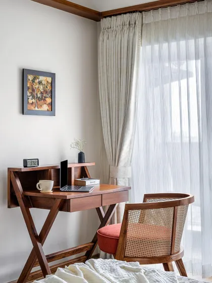 The study nook in the 'Gulmohar' primary room, featuring a classic wooden desk and a cane-back chair. The space is perfect for work while enjoying the view from the large window.