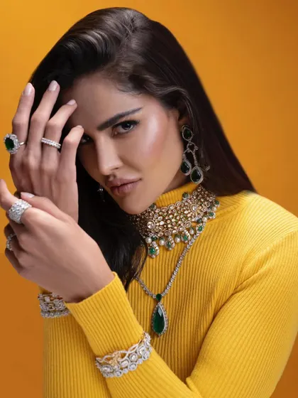 A powerful and confident pose from the emerald and diamond shoot. The combination of the yellow turtleneck and layered green jewelry creates a visually stunning and memorable look.