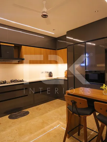 This kitchen features a bold combination of dark grey and wood-finish cabinets. A small breakfast nook provides a cozy spot for quick meals, demonstrating efficient use of space.