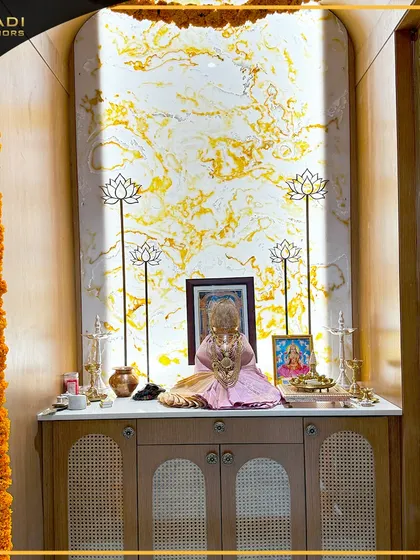A modern puja altar with a backlit marble-finish panel and elegant lotus-shaped candle holders. The cane-work on the cabinet doors below adds a touch of earthy texture.