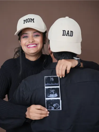 Officially Mom and Dad. This creative shot with "Mom" and "Dad" caps and the ultrasound scan is a fun and modern way to announce your new roles to the world.