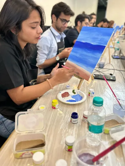 A painter concentrating on the waves and sand of her beach scene.