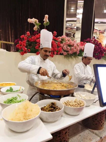 A chef preparing a large batch of noodles in a traditional kadai. This image showcases our ability to cater to large crowds with authentic Indian and Asian cooking methods.