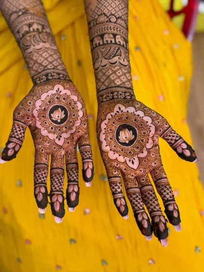 Srijani's wedding mehendi, a beautiful design with a central lotus mandala, set against a vibrant yellow backdrop.