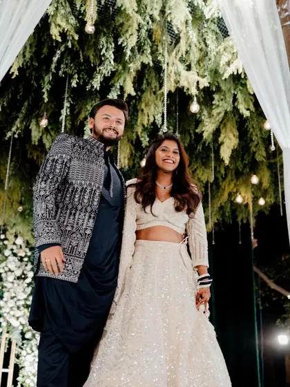 The couple poses on their beautifully decorated Sangeet stage, under a canopy of hanging foliage and lights.