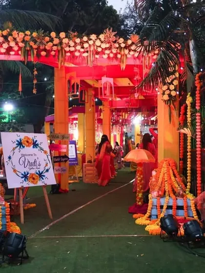 The same Haldi entrance seen at dusk. With the addition of spotlights and fairy lights in the trees, the colorful setup takes on a magical glow, ensuring the festive vibe continues into the evening.