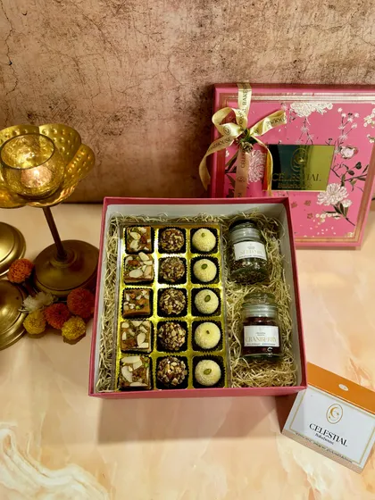 The 'Bliss Box' includes Roasted Almond Truffles, Rose & Pistachio Shortbread, Coconut Ladoos, and jars of Super Seed Mix and Dried Cranberries.