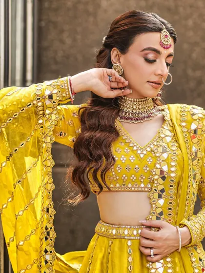A close-up portrait of the bride in her vibrant yellow Mehendi outfit, looking down with a gentle smile.