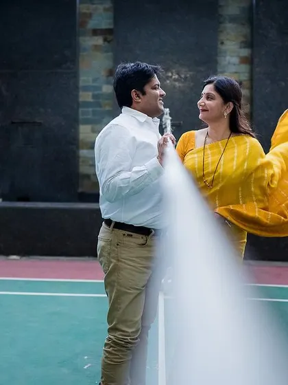 A creative anniversary photo taken on a badminton court, using the net as a foreground element to frame the couple.