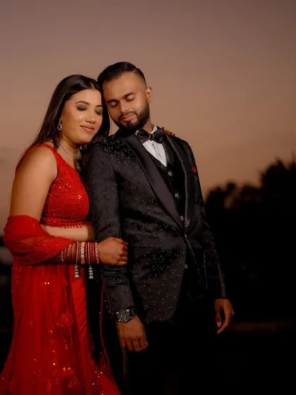 A romantic portrait of Monika and Mukul against the sunset sky at their reception.