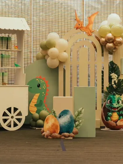 A "3-Rex" dinosaur theme for a third birthday. The setup includes a cute dinosaur egg prop, a cart for favors, and a color palette of sage green and beige for a modern prehistoric look.