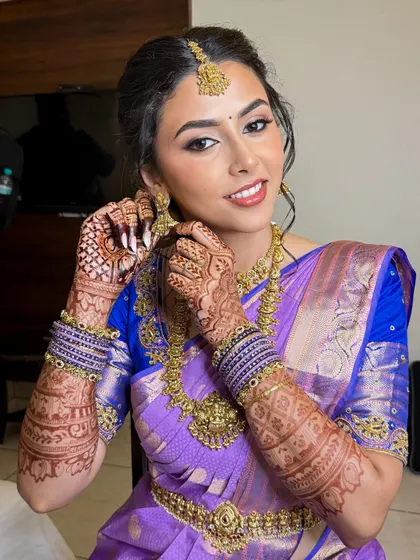 A candid moment of the bride getting ready. Her natural smile shines through, complemented by a makeup look that feels light and comfortable.