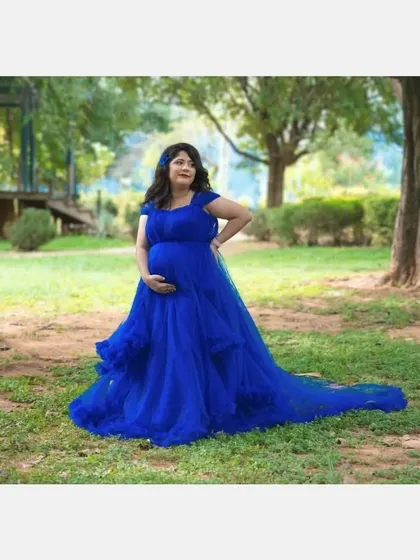 A solo portrait of the expecting mother in the royal blue ball gown. The dress's vibrant color and full skirt make it a standout piece for any location.