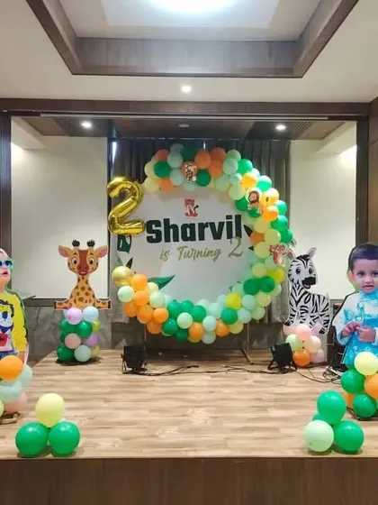 A jungle-themed stage decoration for a second birthday, with various animal cutouts and a circular backdrop.