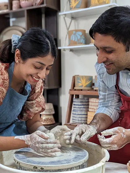Guiding a partner's hands on the wheel is a classic pottery moment. It's a fun challenge in teamwork and makes for a great photo.