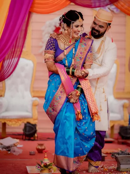 A candid moment of affection as the groom embraces his bride from behind during their Maharashtrian wedding ceremony.