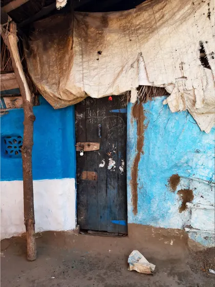 A rustic door on a bright blue wall, patched with tarpaulin. I find so much beauty in these makeshift, lived-in spaces.