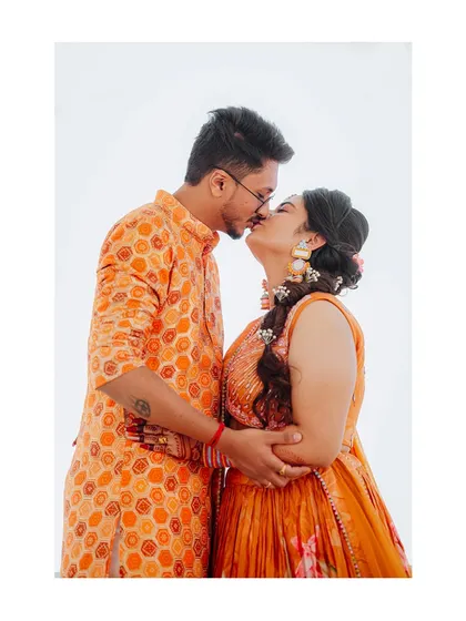 An intimate kiss shared by the couple during their Haldi ceremony, showcasing their love amidst the vibrant celebration.