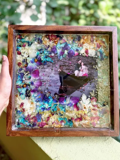 A closer look at the vibrant preserved orchids from a wedding varmala, set within a rich teakwood frame. The details, from the names to the gold flakes, make this piece a truly personal story frozen in time.
