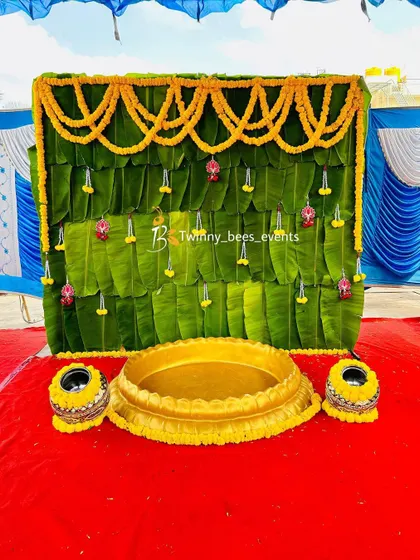 Another view of our banana leaf Haldi decor, this time on a red carpet. The vibrant green of the leaves contrasts beautifully with the yellow marigold toran and decorated pots.