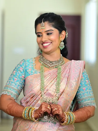 A portrait of the bride, highlighting the intricate floral embroidery on the sleeves of her light blue blouse.