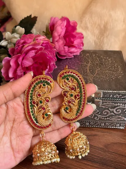 Another beautiful shot of the peacock ear cuffs against a floral background.