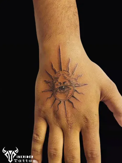 A watchful eye within a sun, tattooed on the hand. This fine-line piece is a symbol of protection and powerful energy, placed in a highly visible spot.