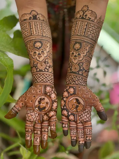 A beautiful example of personalized bridal mehendi. This design features portraits of the bride and groom, with the groom's name, "Preetham," elegantly written across the bride's fingers.
