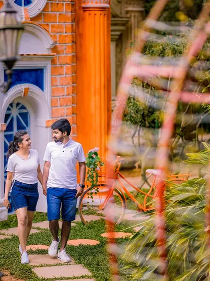 A candid shot of the couple taking a stroll. Their matching casual outfits and the colorful background create a fun, slice-of-life pre-wedding photo.