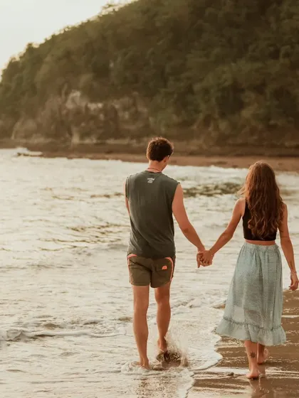 A couple walks hand-in-hand along the water's edge in Bali. This classic romantic shot captures the beginning of their journey together in a beautiful destination.