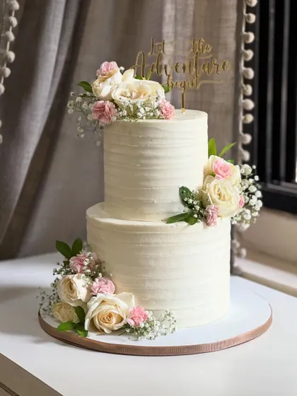 Simplicity meets elegance in this floral white beauty. Adorned with fresh blooms and timeless textures, this minimal two-tier cake is proof that sometimes, less truly is more.