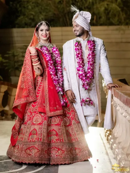 A beautiful full-length portrait of the couple, showcasing the bride's intricate red lehenga.
