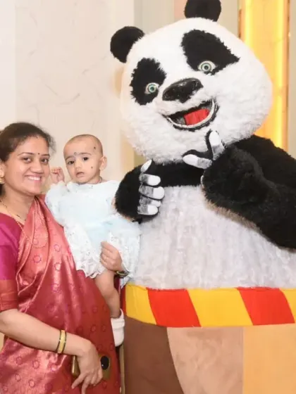 A mother and her baby pose with the friendly panda mascot at the birthday party.