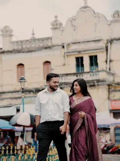 A couple in traditional attire walks hand-in-hand through a historic city market, capturing a blend of romance and local culture.