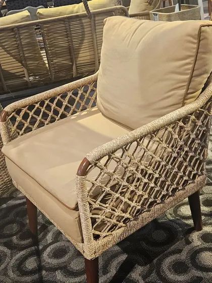 This armchair showcases a beautiful combination of a wooden frame and intricate rope weaving, offering both comfort and a sophisticated aesthetic.