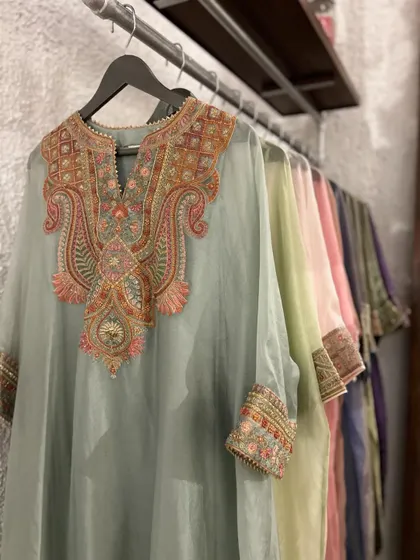 A rack of beautifully embroidered organza kurtas in a palette of soft pastels. This shows the variety of colors available in a single, elegant style, making it easy to find your perfect shade.