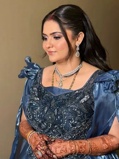 A side profile of the bride in her blue reception gown. The soft curls and glowing makeup create a look of pure elegance.