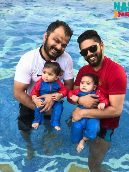 Two dads enjoying a swim class with their twin babies, a perfect example of family fun.